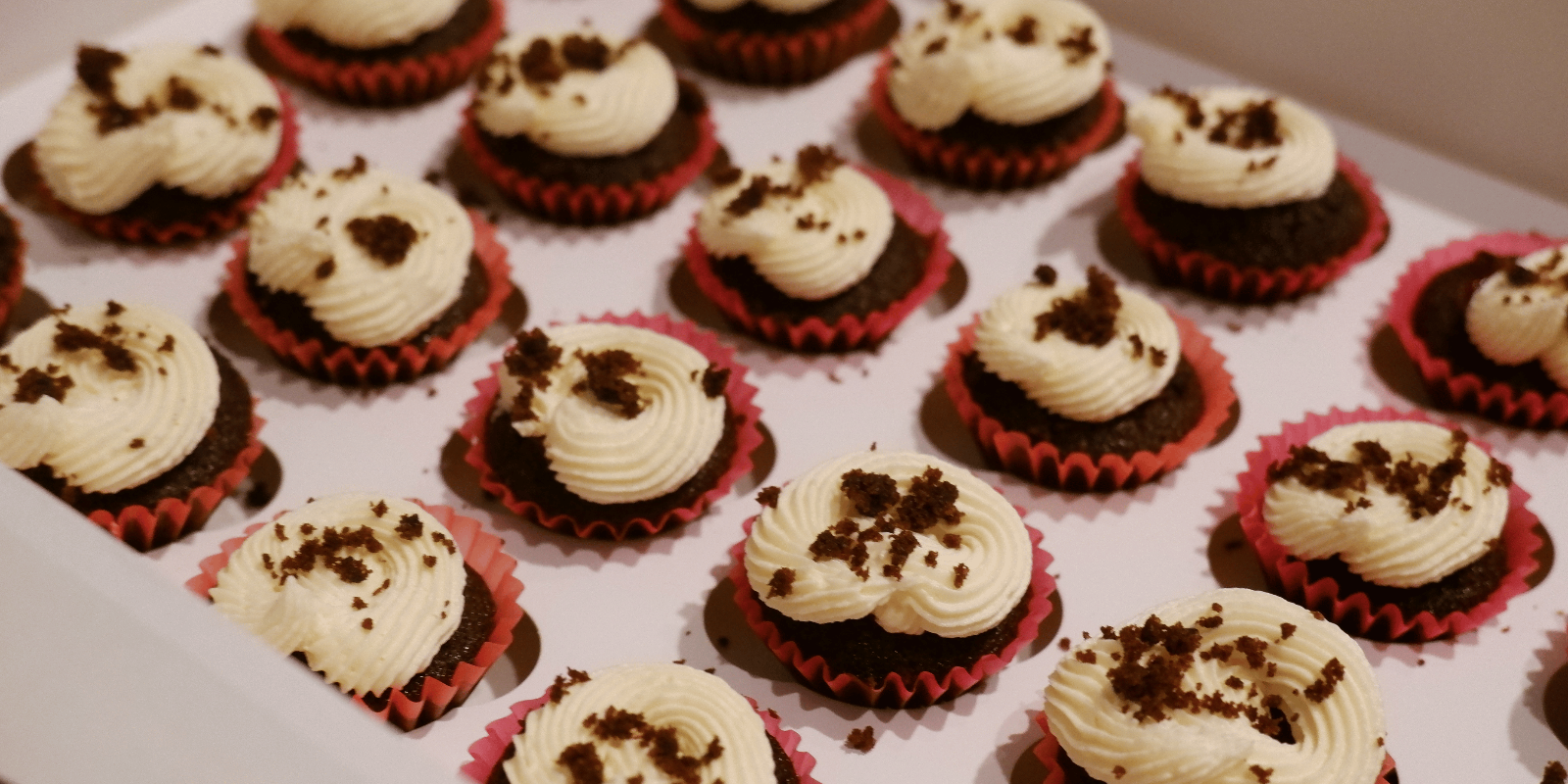 Mini red velvet cupcakes with some cake crumbs at the top.