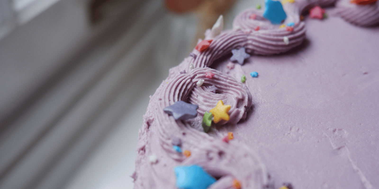 Colourful lilac birthday cake with rainbow stars.
