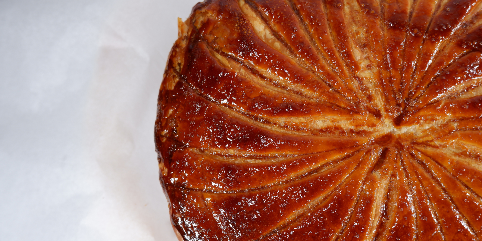 Close up of a galette des rois, a french pastry made during the first few days of January. The galette is shiny and look very crispy. It is filed with an almond filing.